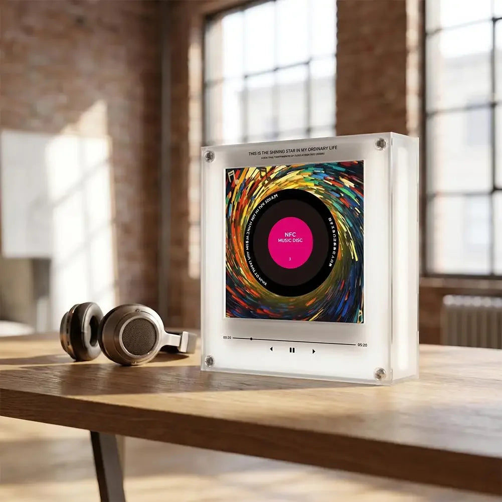 Clear acrylic NFC music player with a colorful vinyl disc and built-in speaker, next to headphones on a wooden table.